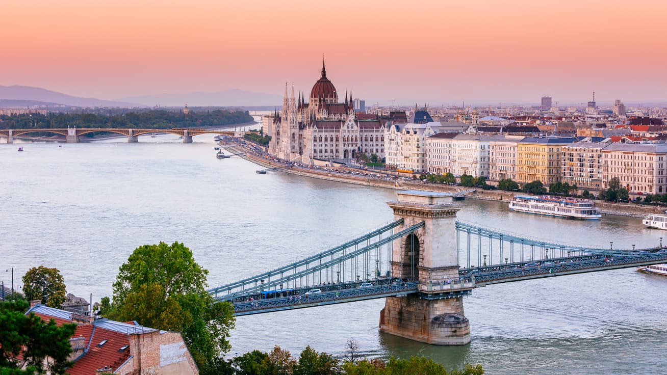 Chain Bridge and Hungarian Parliament Building along the Danube River in Budapest at sunset.