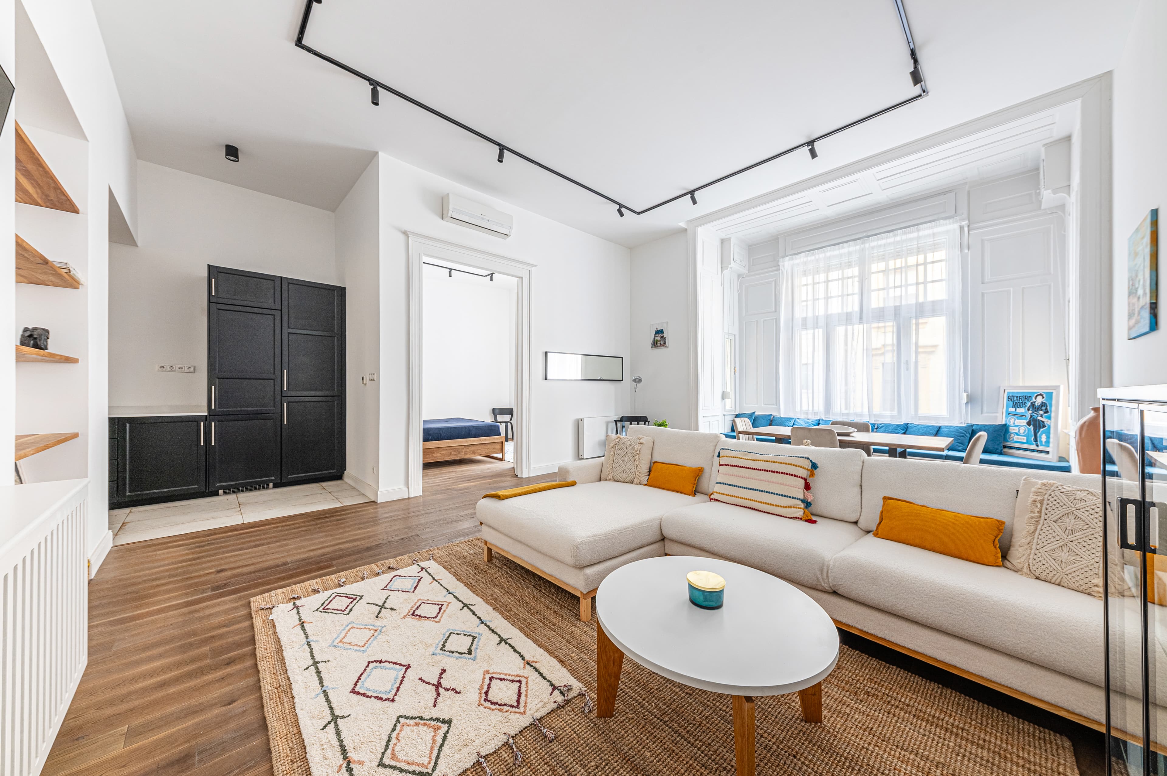 Modern living room with white sectional sofa, colorful pillows, and large window with seating.
