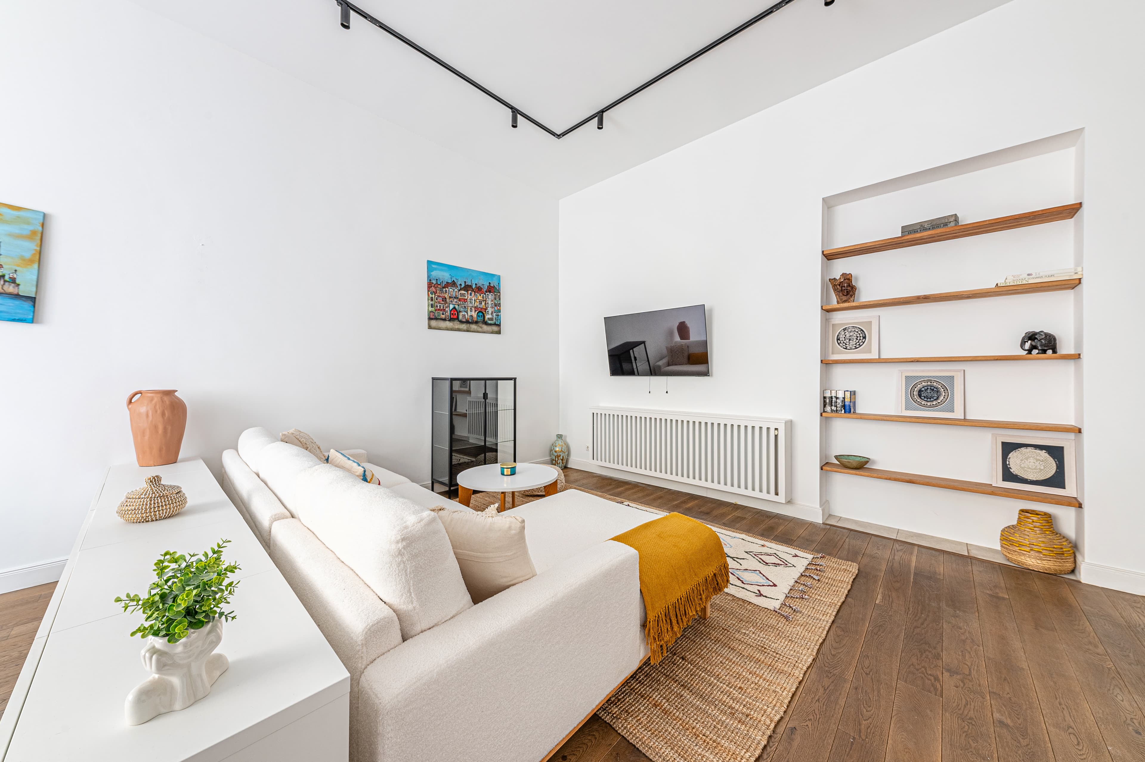 Bright living room with white sectional sofa, built-in wooden shelves, and dark wood floors.